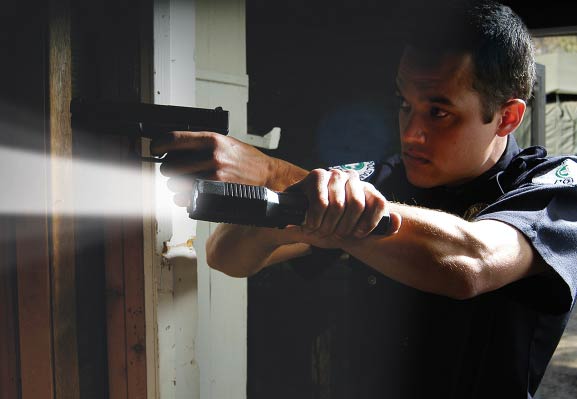 A police officer holding a tactical flashlight with a pistol